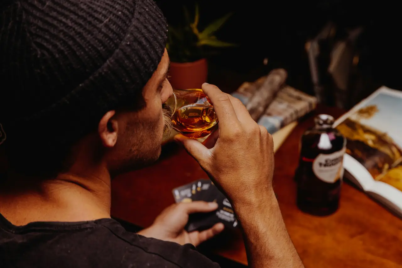 Ein Barkeeper mit Mütze probiert Whisky an einem Bartisch
